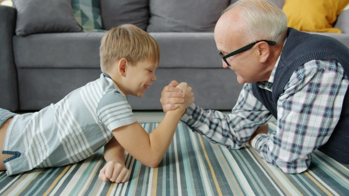 Grandfather and grandson arm wrestling on the floor